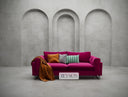Pink sofa with colorful cushions against a gray concrete wall.